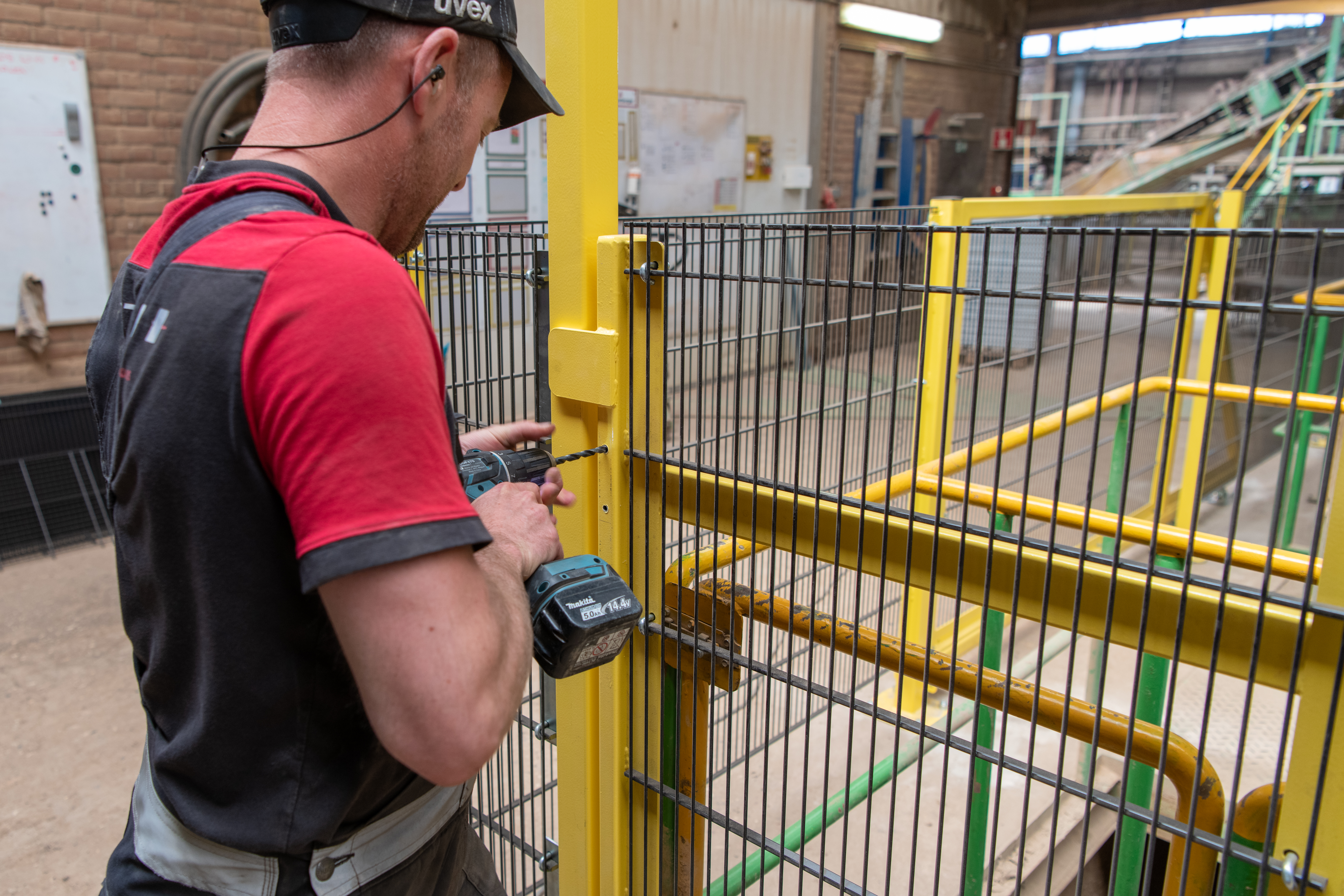 Intech monteur installeert veiligheidshekwerk voor machineafscherming bij productie-installatie